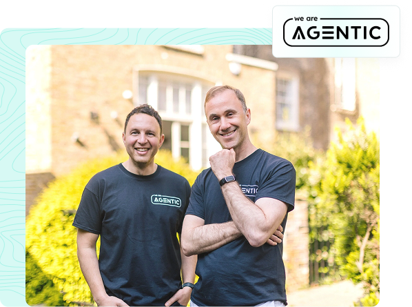 Two men standing outdoors, smiling, wearing black t-shirts with 'We are AGENTIC' logo, in front of a house and greenery.